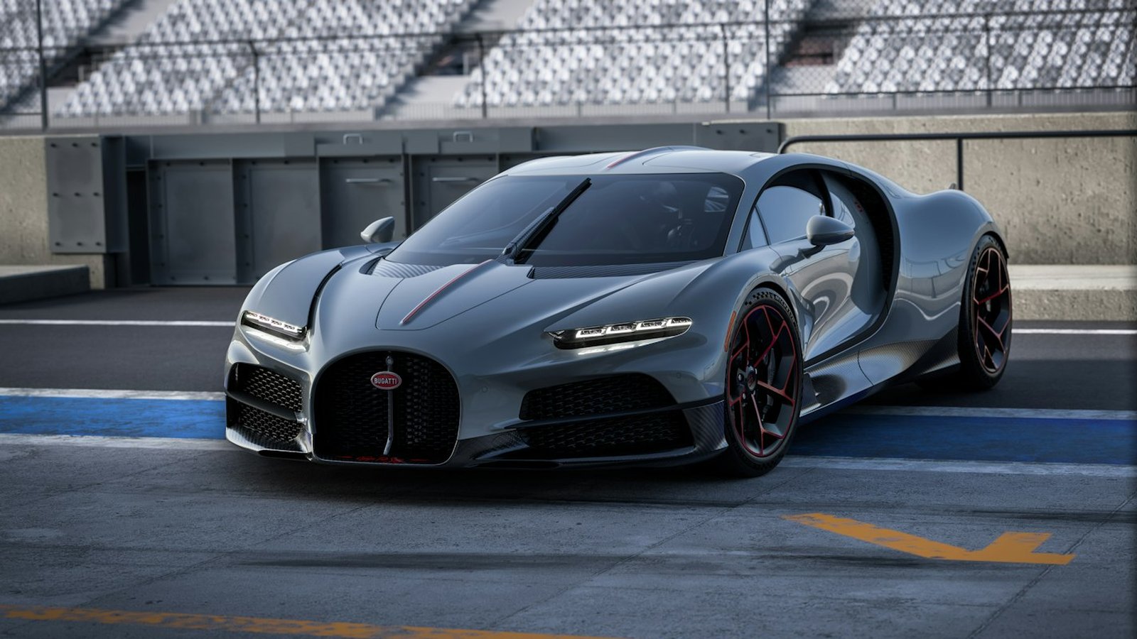 Grey Bugatti Tourbillon Équipe Pur Sang with red-accented wheels parked in a race track pit lane