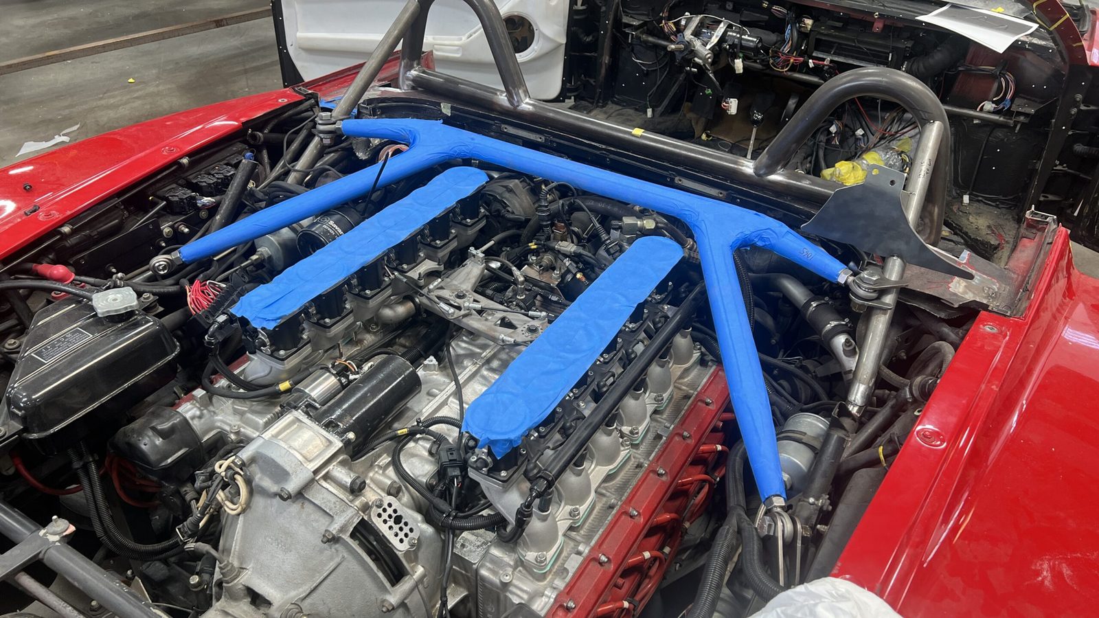 Testarossa engine bay during the build, with new roll hoops and bracing taped in blue