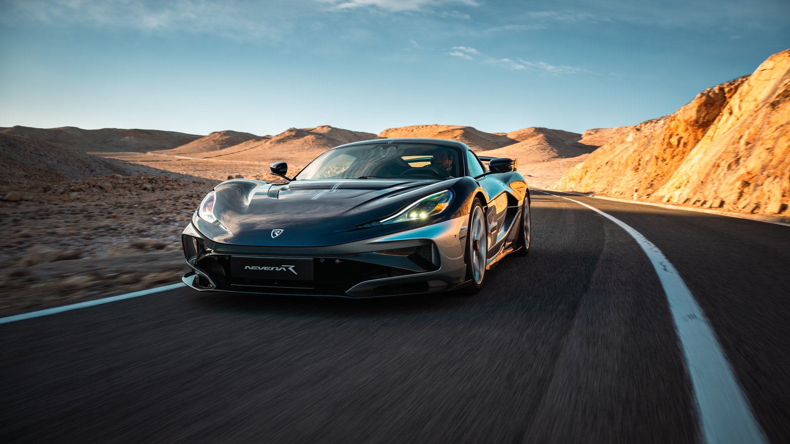 Dark grey Rimac Nevera R Founder's Edition driving on a desert mountain road at sunset
