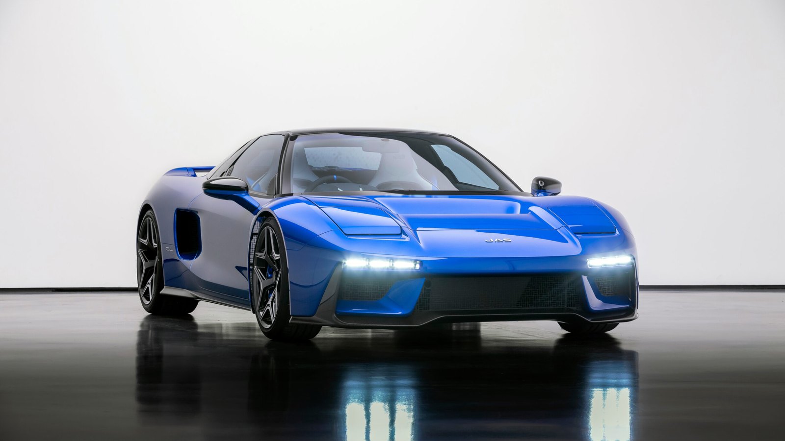 Blue JAS Tensei, a carbon-bodied rebuild of the first Honda NSX, seen from the front three-quarter in a white studio with slim LED headlights
