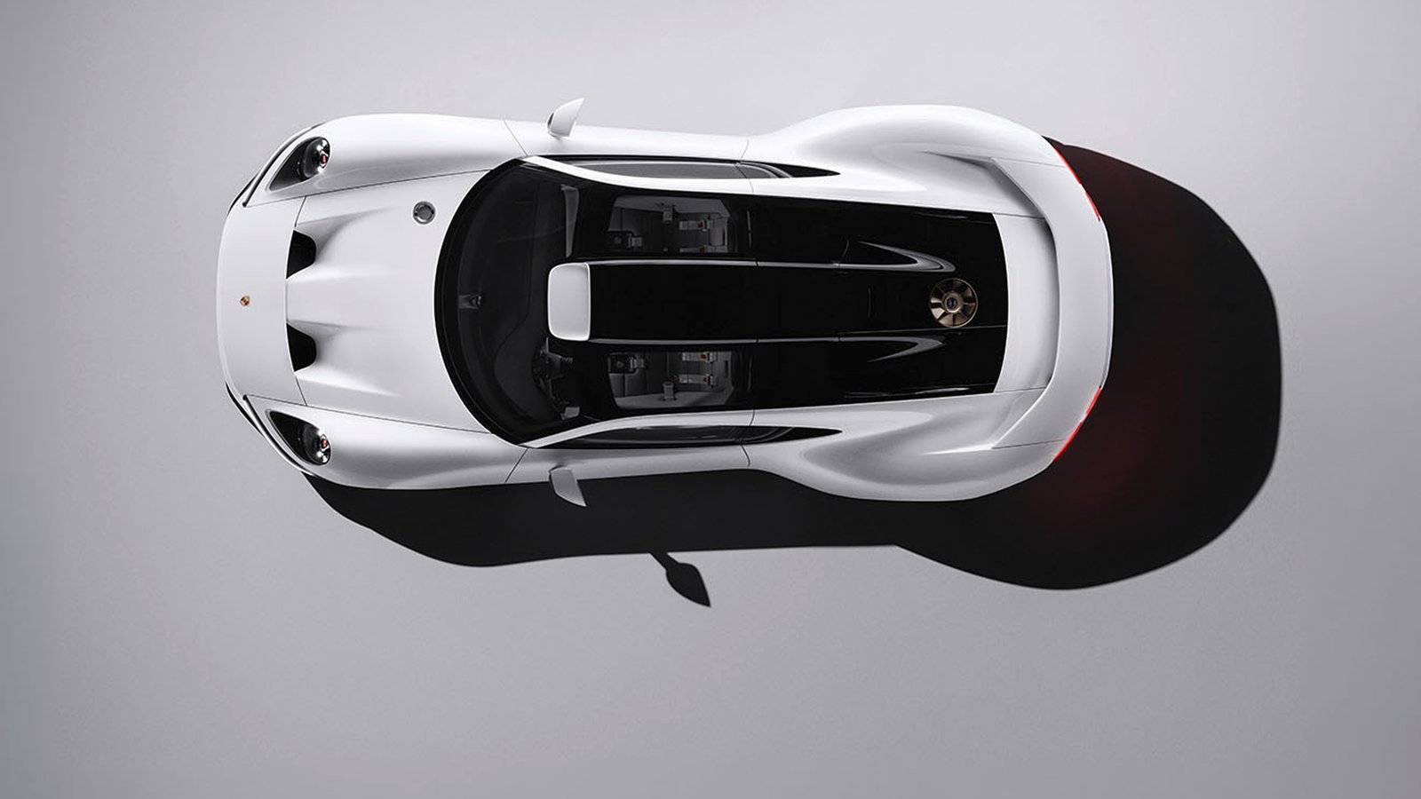 Overhead view of the white Porsche Mission S showing round headlights, a vented front hood, a dark glass canopy with two seats visible, and a bronze-colored cooling fan in the rear deck